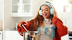 Cooking, headphones and pot with woman in kitchen of home for health, organic diet or nutrition. Music, stirring and streaming with person in apartment for culinary dish or gourmet food preparation