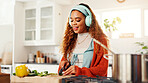 Cooking, cutting and headphones with woman in kitchen of home for health, organic diet or nutrition. Knife, music and streaming with person at counter in apartment for culinary food preparation
