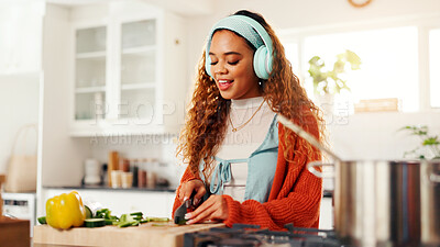 Buy stock photo Cooking, cutting and headphones with woman in kitchen of home for health, organic diet or nutrition. Knife, music and streaming with person at counter in apartment for culinary food preparation