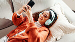 Headphones, relax and woman with phone on couch, search music library and listening to podcast. Audio tech, relax and person with radio app for streaming in home, scroll social media and watch video
