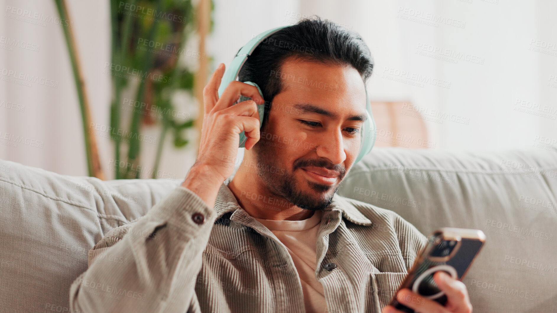 Buy stock photo Relax, man or phone with headphones on sofa for social media video, music album or weekend break. Smile, person and smartphone in home for listening to podcast, sound playlist and streaming service