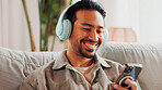 Happy, man or phone with headphones on sofa for streaming music, social media or weekend break. Relax, person or smile with smartphone in home for listening to podcast, sound playlist or subscription