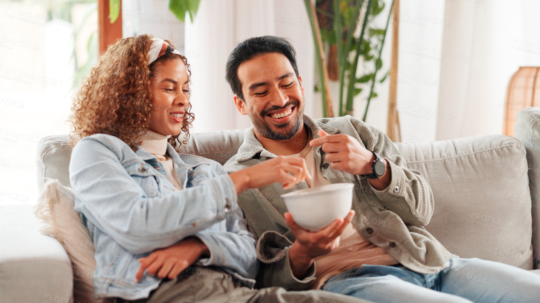 Buy stock photo Home, bowl and happy couple on sofa, relax and bonding together with love, eating and calm. Apartment, snack and man on couch, woman and weekend break with entertainment, smile and food in lounge
