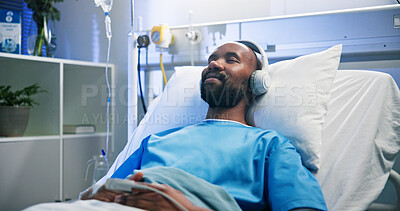 Buy stock photo Black man, relax and smile with headphones in hospital bed for streaming music, podcast and recovery. Male person, inpatient and listening to audio of playlist, album and healing sound from operation