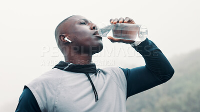 Buy stock photo Fitness, black man outdoor and drink water with earbuds for music playlist, workout break or below. Person, beverage and audio tech in nature with streaming service, album and hydration for exercise.