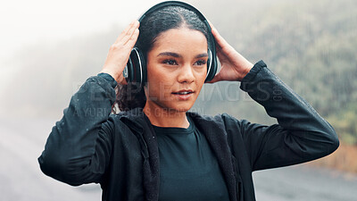 Buy stock photo Fitness, rain and woman with headphones outdoor to start running, music playlist and cardio podcast. Athlete, person and ready for exercise in road with audio streaming, wellness workout or raindrops