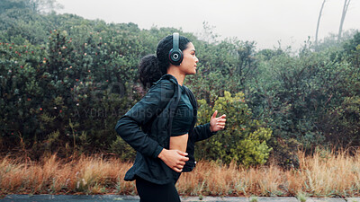 Buy stock photo Fitness, woman and running with headphones in road for exercise, music playlist and cardio podcast. Athlete, person and workout in nature with audio streaming, pace training and endurance challenge