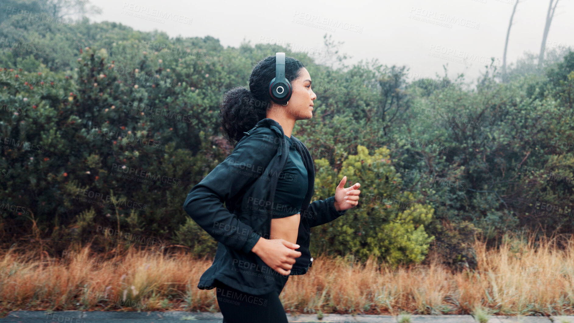 Buy stock photo Fitness, woman and running with headphones in road for exercise, music playlist and cardio podcast. Athlete, person and workout in nature with audio streaming, pace training and endurance challenge