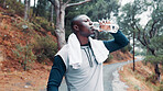 Fitness, black man and drink water in forest with towel for wellness, workout break or recovery. Active person outdoor, beverage and cloth in nature with exercise rest for hydration, relax or thirst.
