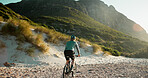 Man, bicycle and sand with mountain for cycling journey, fitness or outdoor adventure in nature. Back view, male person or cyclist with bike on rocky shore for exercise, commute or ride in wilderness