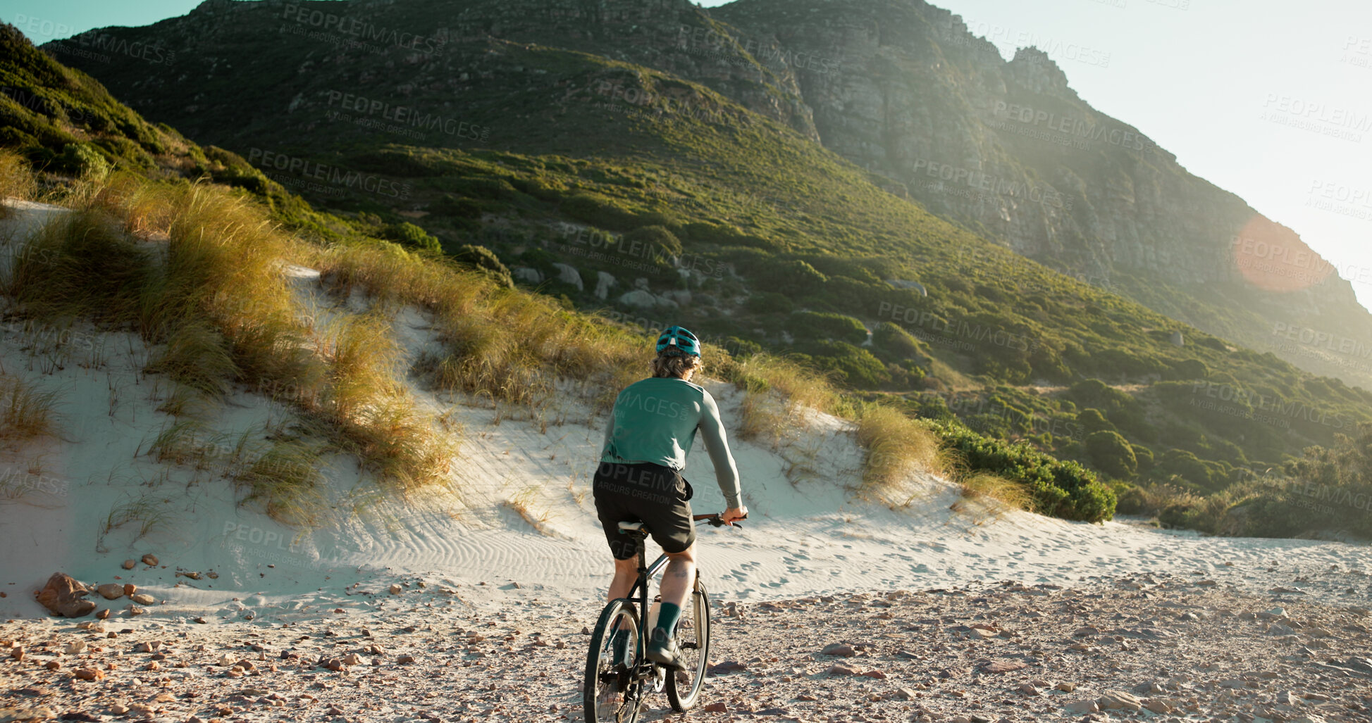Buy stock photo Man, bicycle or sand with mountain for cycling journey, fitness or outdoor adventure in nature. Back view, male person or cyclist with bike on rocky shore for exercise, training or ride in wilderness