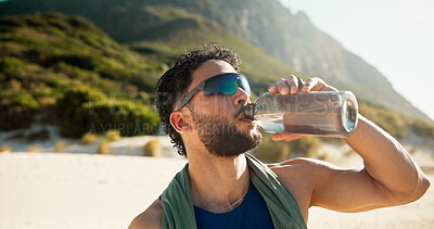 Buy stock photo Fitness, break and man with drinking water by beach, hydration and sunglasses for summer training. Running pause, beverage and athlete with bottle for workout recovery, rest and outdoor with liquid