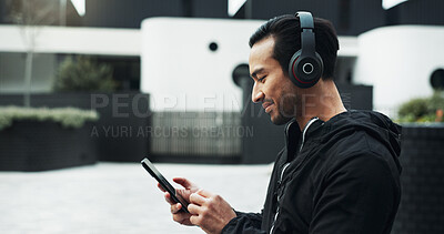 Buy stock photo Fitness, music and phone with man in city for cardio training, running or workout tracking. App, exercise and headphones with athlete or runner typing on mobile for outdoor challenge or sports