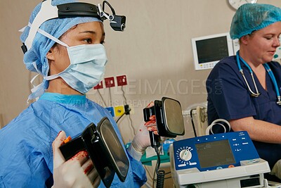 Buy stock photo Medical, defibrillator and surgeon in surgery at hospital with service for heart attack. Operation, treatment and female doctor with healthcare equipment for cardiac shock in emergency room at clinic