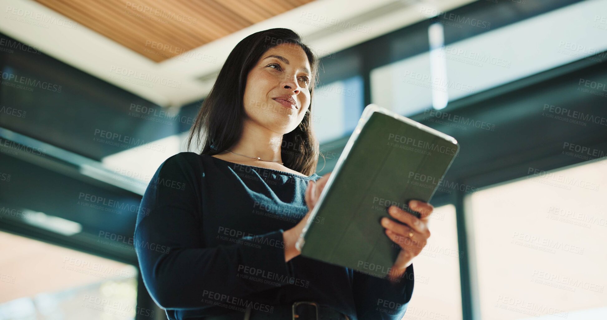 Buy stock photo Woman, realtor and tablet in office for thinking, property management and service review. Low angle, estate agent and digital tech in agency for commission update, scroll and smile for reflection