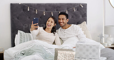 Buy stock photo Selfie, couple and celebration in bedroom with Christmas, profile picture and festive season for memory. Home, man and woman with present in bed for photography, smile and social media on holiday