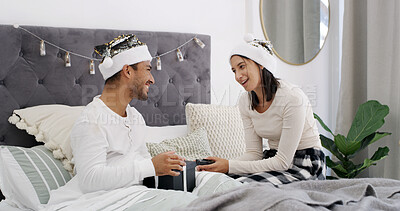 Buy stock photo Laughing, couple and celebration in bed with Christmas, present and festive season for love in home. House, man and woman with gift in bedroom for Santa hat, smile and decoration for holiday bonding