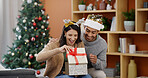Christmas, couple and smile in living room with present for holiday tradition, connection and gratitude. Happy, married people and gift in house for festive season, appreciation and bonding together.