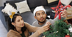 Christmas, tree and couple with decoration in home for festive tradition, holiday season and celebration. December, love and man with woman with bauble, ornament and star for xmas, vacation and event