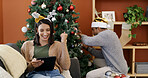 Christmas, fist pump and tablet with woman on sofa in living room of home for decoration success. App, celebration and person in lounge with man decorating tree for season or tradition as couple