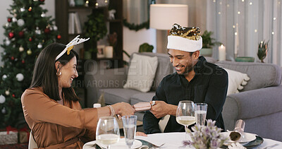 Buy stock photo Happy, couple and Christmas cracker in home, romance and excited for present, alcohol or celebration. Laughing, man and woman on festive season, love and fun on December holiday and bonding in house