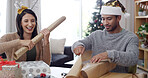 Christmas, present and wrapping paper with couple in living room of apartment for festive tradition. Celebration, gift and teamwork with happy people in home for December or xmas holiday season