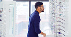 Eye care, man and customer shopping for glasses, vision and eyesight improvement with choice. Store, eyewear and person with frame for optometry, check spectacles and lens for health at shelf