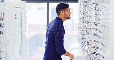 Buy stock photo Eye care, man and customer shopping for glasses, vision and eyesight improvement with choice. Store, eyewear and person with frame for optometry, check spectacles and lens for health at shelf