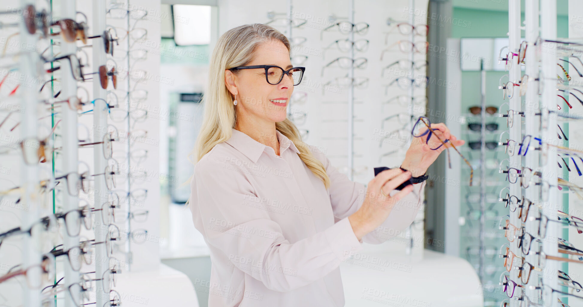 Buy stock photo Vision, woman and cleaning glasses in store, eye care and maintenance of stock with smile. Shop, eyewear and mature person with cloth fabric for frame, optometrist and check spectacles for health