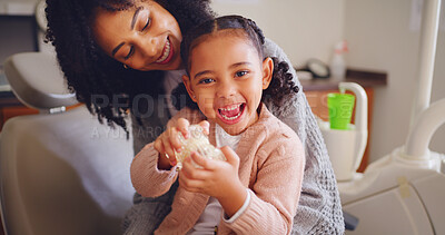 Buy stock photo Happy child, mother and tooth model at dentist office for learning oral health, play and excited. Mom, girl and pediatric orthodontics with teeth, typodont and dental care with parent for portrait