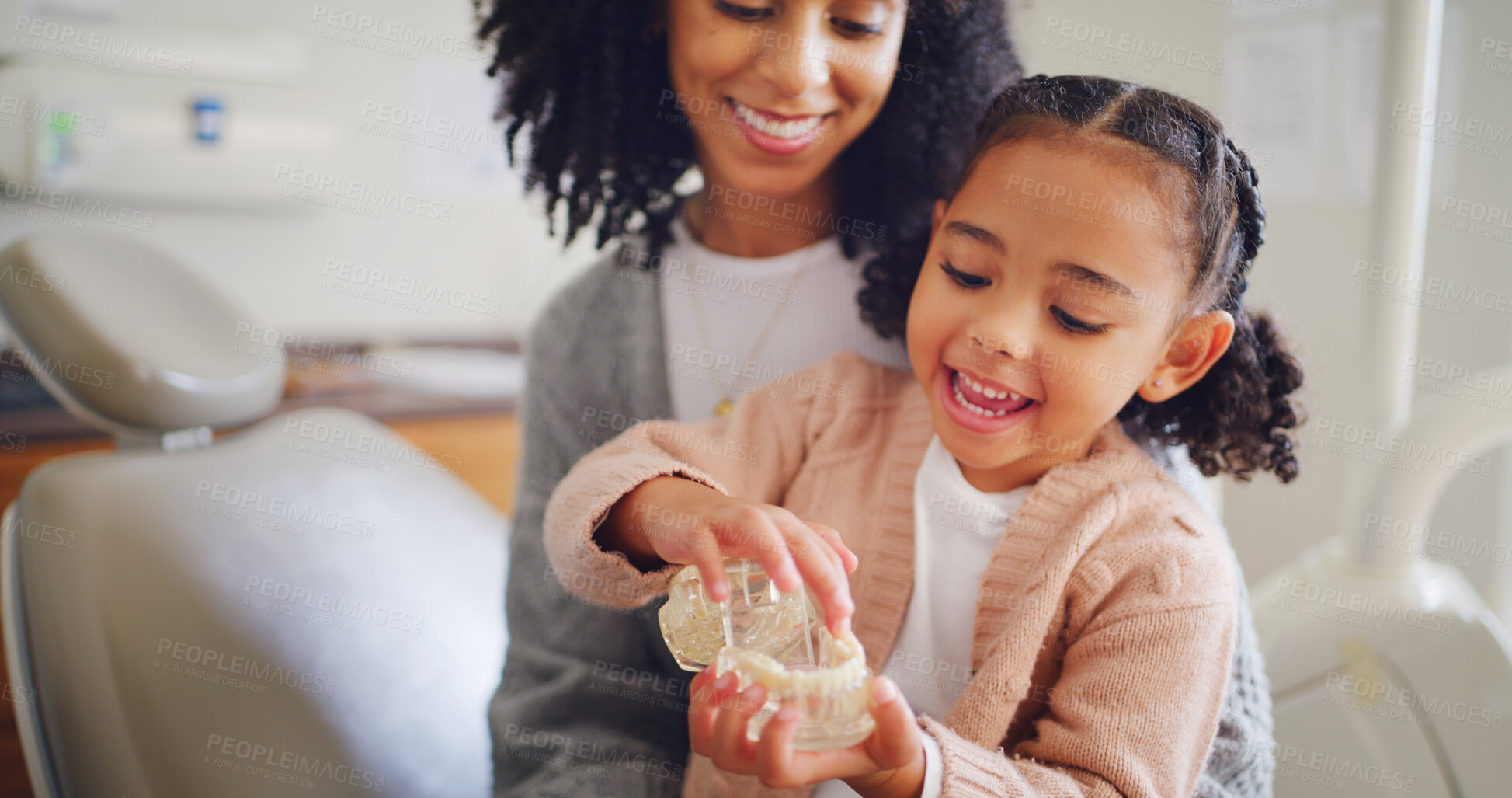 Buy stock photo Happy child, mother and tooth model for dental wellness, learning and oral health in dentist office. Mom, girl and pediatric orthodontics with teeth, education and play with typodont with parent