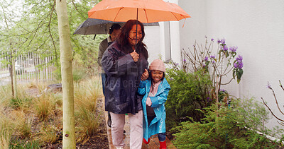 Buy stock photo Raining, umbrella and grandparents and child outdoor for winter season, support and holding hands. Rainfall, generations and help with people and kid at family home for shelter and storm protection