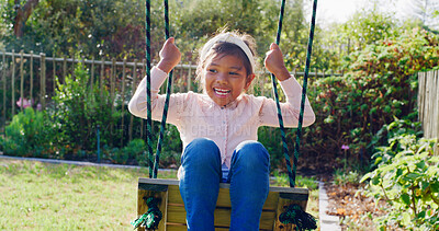 Buy stock photo Happy, kid and swing outdoor in backyard for fun activity, coordination and childhood development. Girl, playing and smile in garden with playground for holiday recreation, wellness or weekend break.