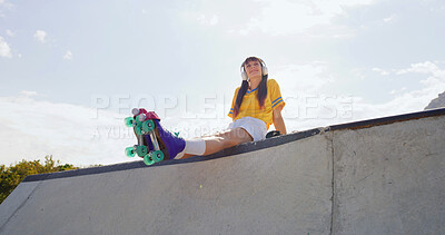 Buy stock photo Woman, roller skates and smile at park with headphones, low angle and listen to music with space in city. Person, skater and happy with streaming subscription, audio or relax on ramp in urban town