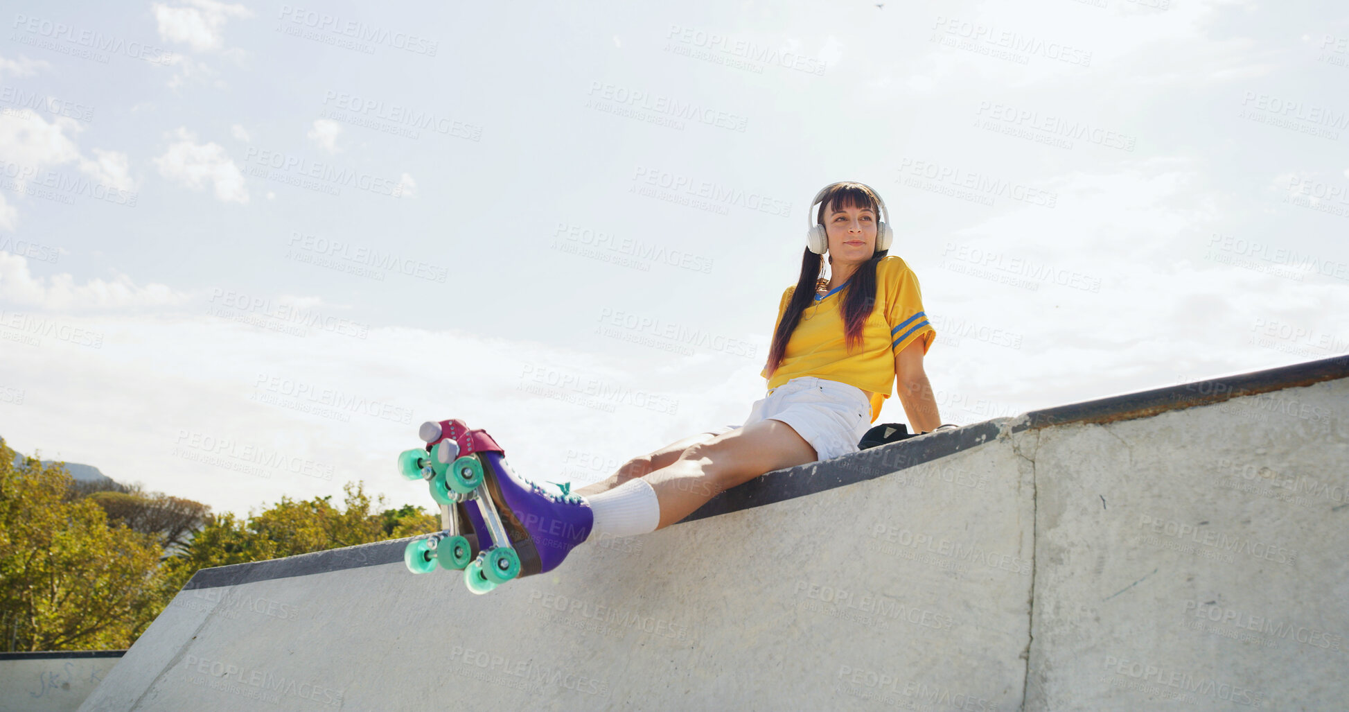 Buy stock photo Woman, roller skates and thinking at park with headphones, low angle and listen to music with space in city. Person, skater and happy with streaming subscription, audio or relax on ramp in urban town
