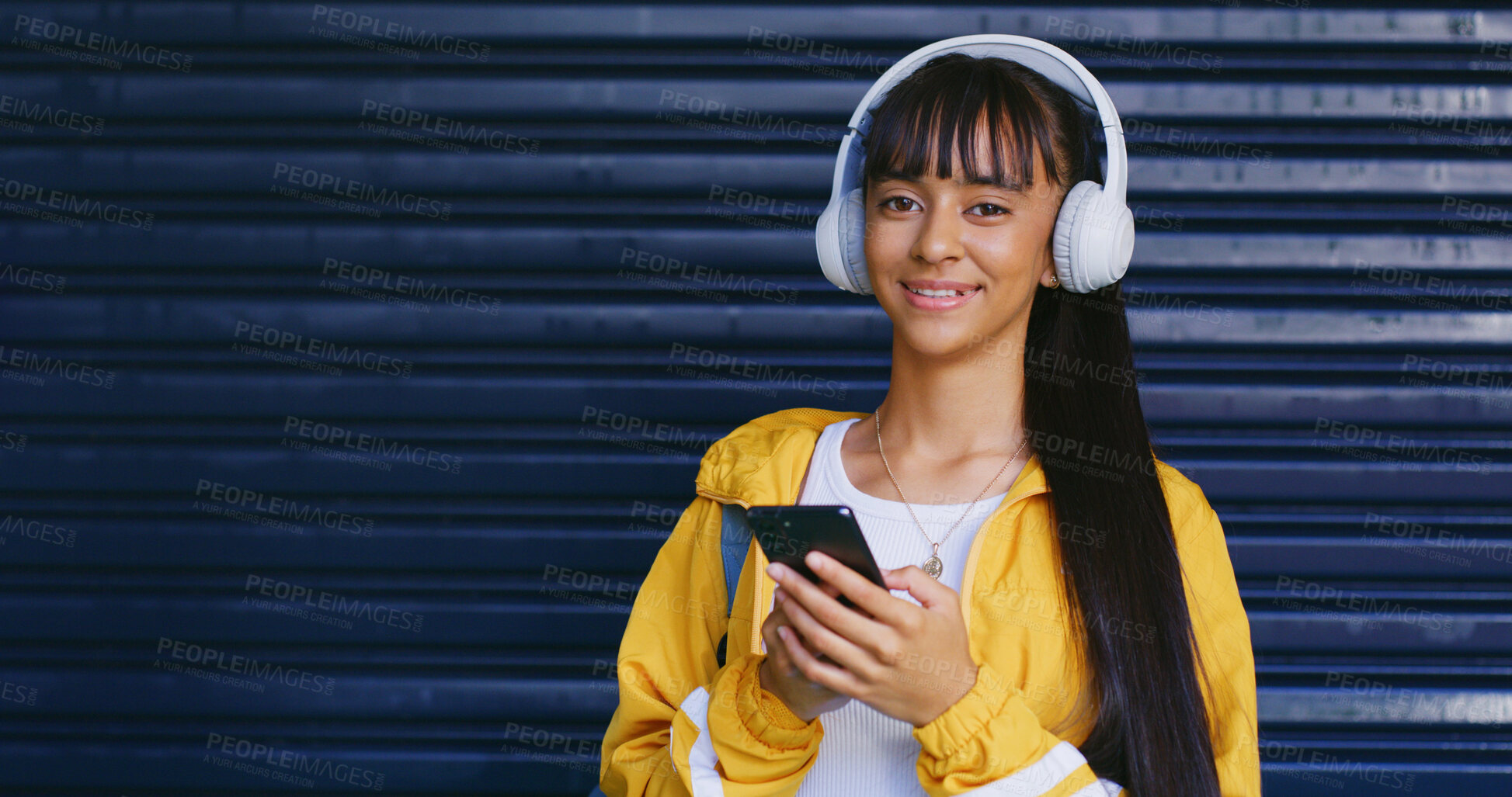 Buy stock photo Music, phone and portrait of girl with garage door mockup for audio streaming or social media. App, space and steel shutter with smile of happy teen in retro fashion for sound listening on headphones