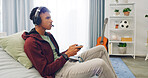 Couch, esport and man playing video game with controller in living room for online and virtual challenge in home. Gamer, headphones and male person for streaming, entertainment or competition
