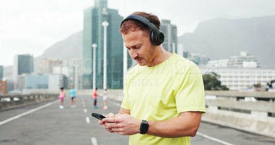Buy stock photo Headphones, phone and man in city for fitness, marathon training and workout outdoor. Sports, exercise and person listening to music, audio and podcast for wellness, health and running in urban town