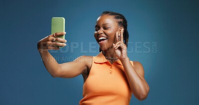 Buy stock photo Peace sign, selfie and social media with black woman in studio for profile picture or status update. App, emoji and photograph with African influencer on blue background for streaming platform