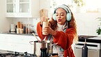 Cooking, music and seasoning with woman in kitchen of home for flavor, food or meal preparation. Cuisine, headphones and pepper with person at counter in apartment for diet, health or nutrition