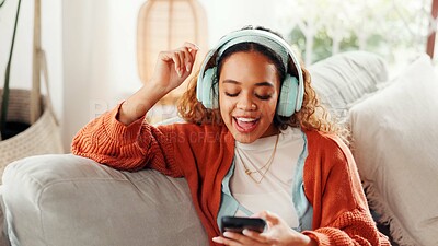 Buy stock photo Headphones, singing and woman with phone on couch, search song library and listening to playlist. Audio tech, relax and happy person with radio app for streaming in home, watch music video or karaoke