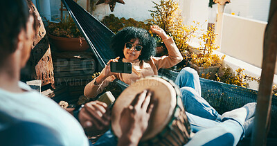 Buy stock photo Outdoor, bongo or couple with mobile on hammock, playing musical instrument or recording video on balcony. Phone, live stream practice or people relax with hand drum in home, sunglasses or chilling