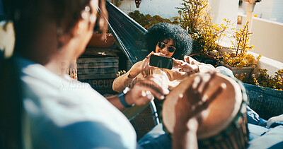 Buy stock photo Outdoor, drum or happy couple with phone on hammock, playing musical instrument or record video on balcony. Mobile app, live stream practice or people with music creation at home, sunglasses or chill