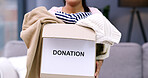 Donation, clothes and hands of person with box in home for for charity, giveaway and welfare. House, living room and woman with parcel, package and collection for clothing, garment and fabric