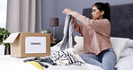 Woman, folding clothes and donation box in home for charity initiative, nonprofit or declutter closet. Female person, apparel and giveaway in package for NGO contribution, support or spring cleaning.