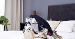 Empty bedroom, clothes and pile of laundry, messy and fabric for housekeeping in home. Bed, dirty textile and unfolded clothing in room interior for chores, chaos and disorganized house in morning