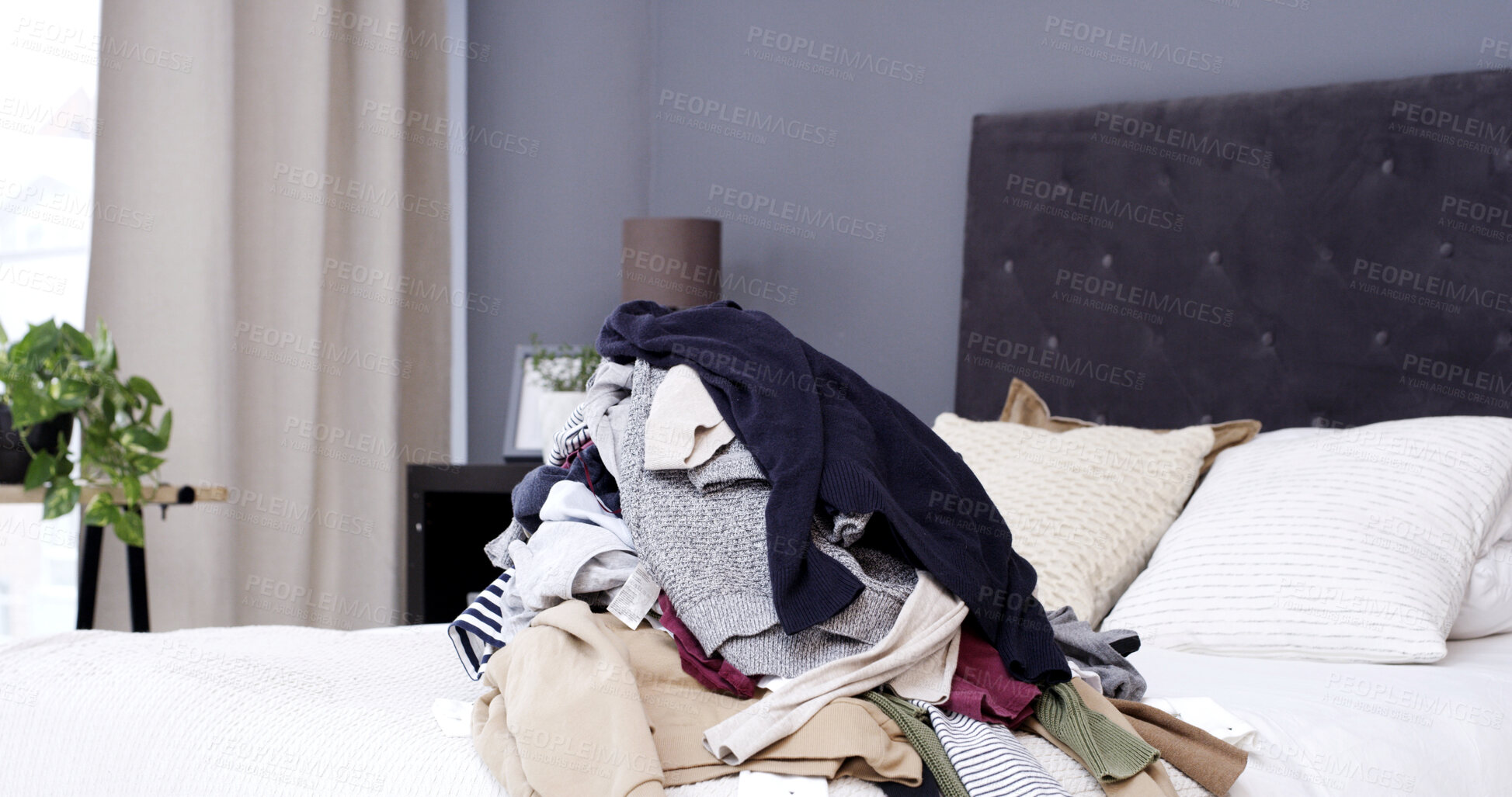 Buy stock photo Empty bedroom, clothes and pile of laundry, messy and fabric for housekeeping in home. Bed, dirty textile and unfolded clothing in room interior for chores, chaos and disorganized house in morning