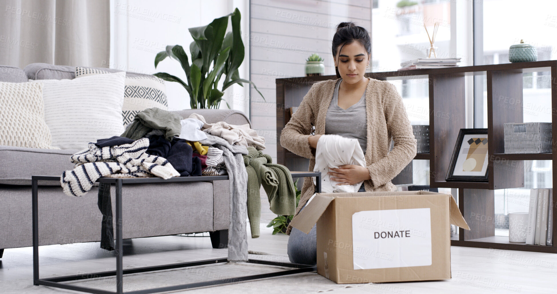 Buy stock photo Woman, fold clothes and donation box in living room for charity initiative, nonprofit or declutter home. Person, apparel giveaway and package in house for NGO contribution, parcel or spring cleaning.