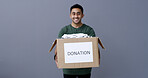 Happy man, portrait and box with donation in studio for charity or welfare on a gray background. Male person, volunteer or model with package or clothing parcel for community service on mockup space