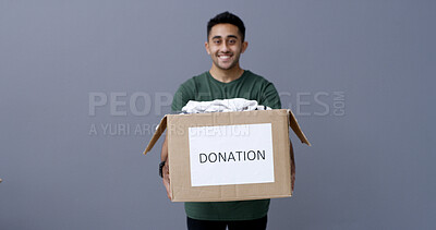 Buy stock photo Happy man, portrait and box with donation in studio for charity or welfare on a gray background. Male person, volunteer or model with package or clothing parcel for community service on mockup space